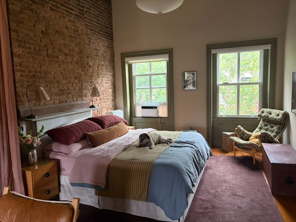 Bedroom with exposed brick wall and layered linens